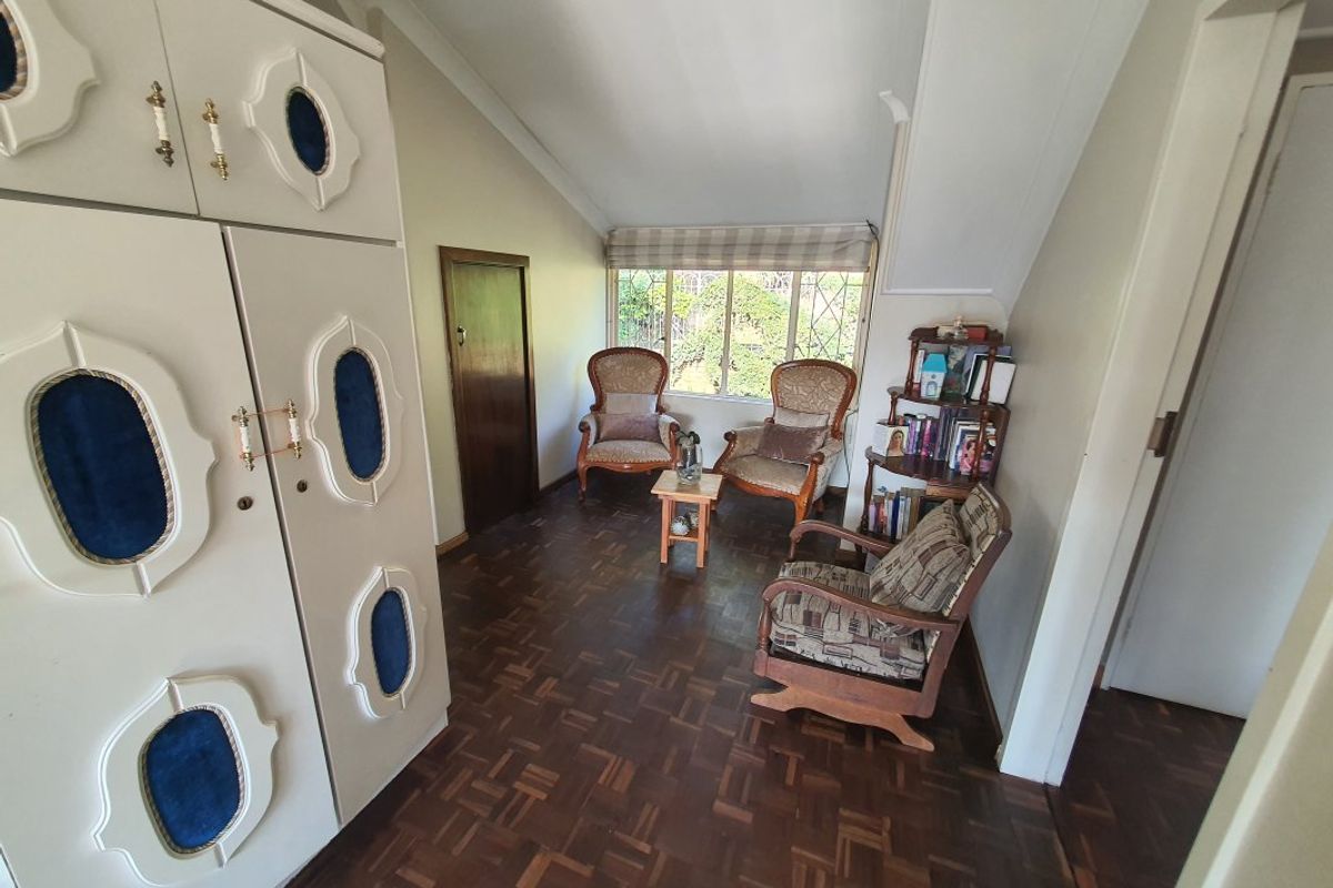 A bedroom featuring parquet flooring, a sloped ceiling, and a large built-in wardrobe with decorative detailing.