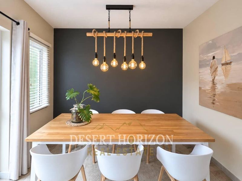 A well-lit dining area featuring a modern rope-style pendant light fixture and neutral wall finishes.