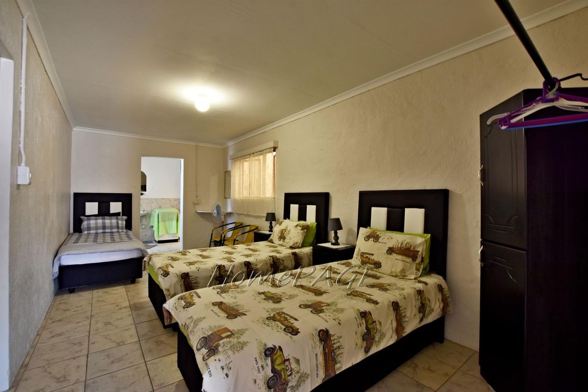 A spacious bedroom featuring tiled flooring and an en-suite bathroom access, providing a functional layout with neutral wall finishes.
