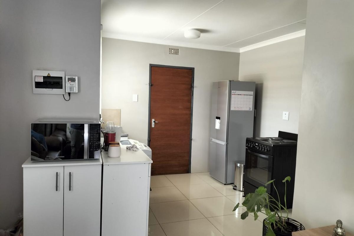 A functional kitchen area featuring tiled flooring, built-in cabinetry, a freestanding stove, and space for a refrigerator.
