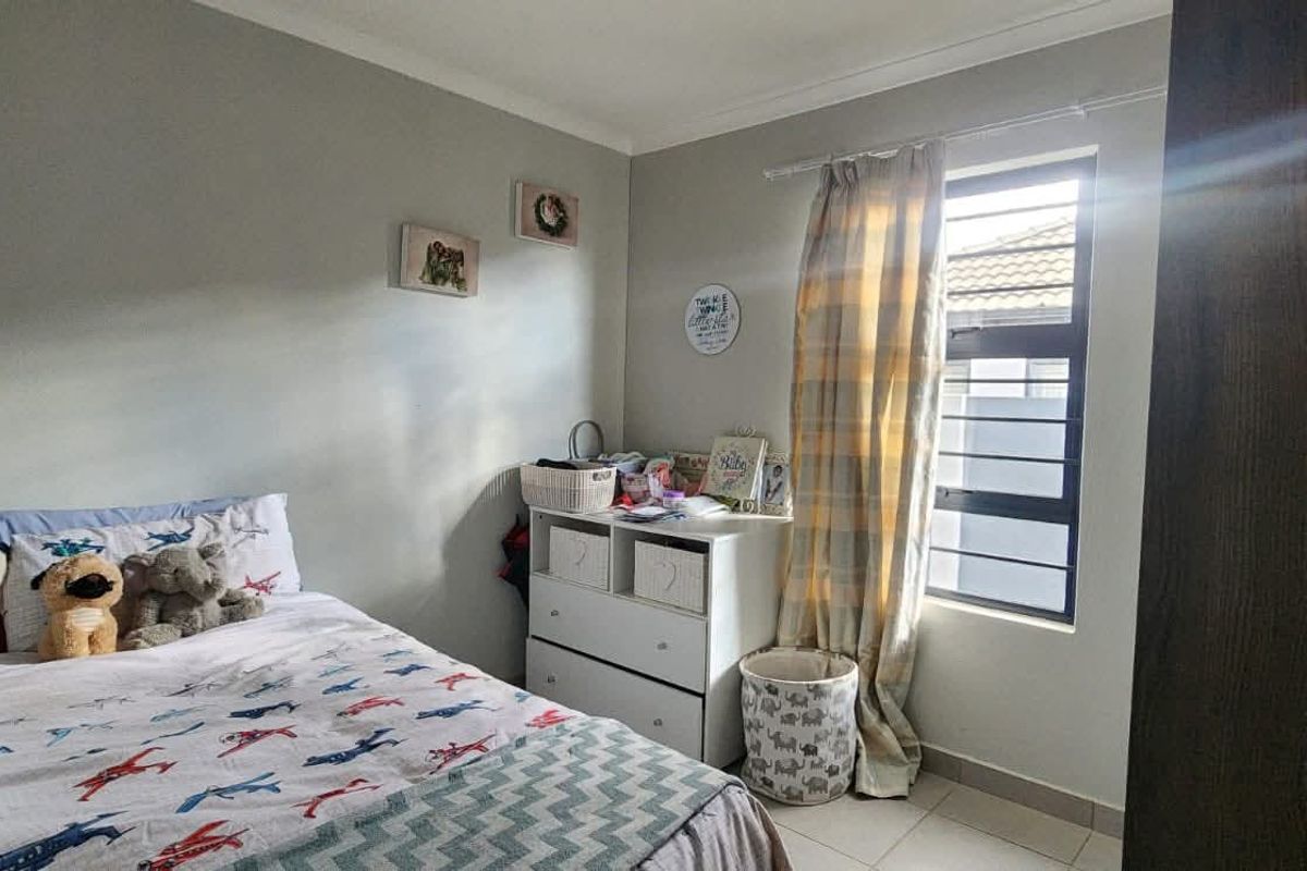 A functional bedroom featuring tiled flooring, a window with security bars, and built-in cupboard space.