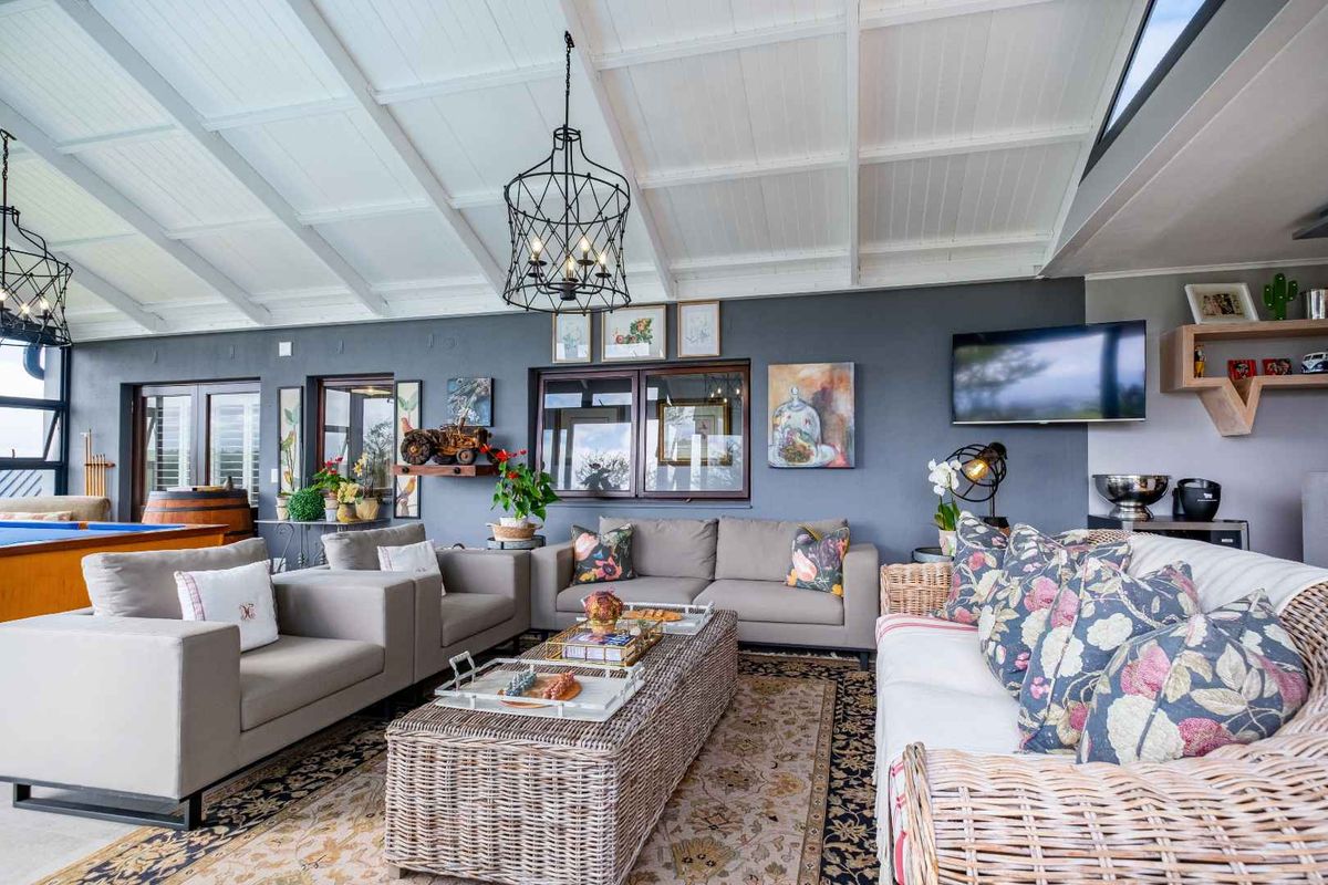 Spacious living area featuring a high vaulted ceiling with exposed beams, large windows, and double doors providing ample natural light.