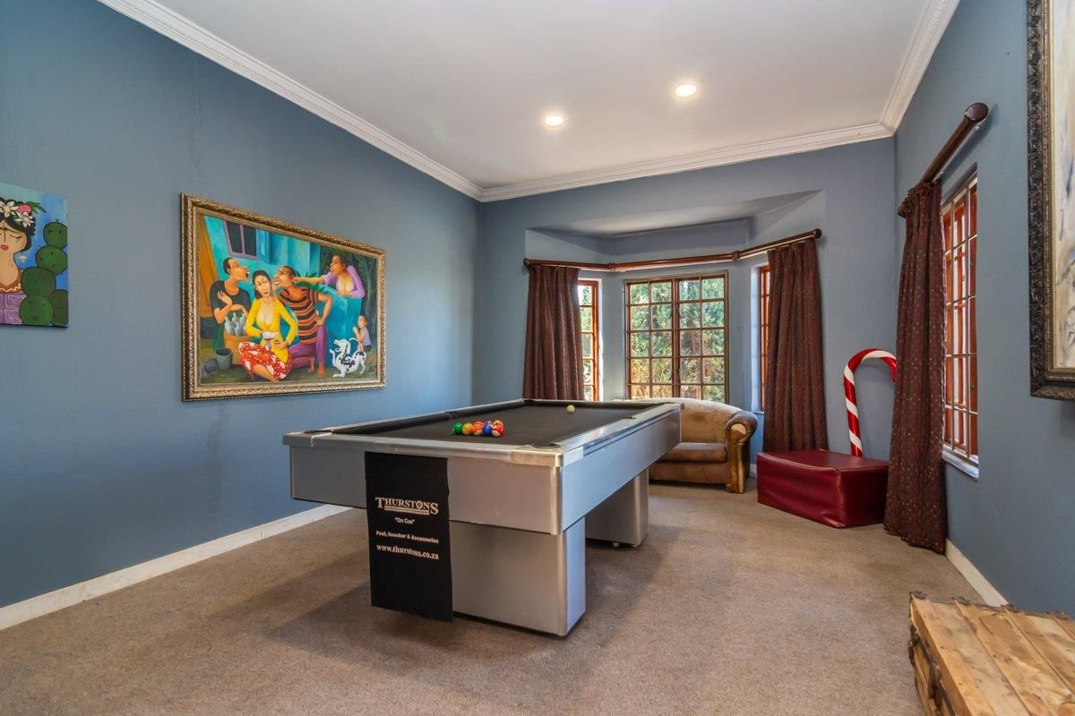 A spacious games room featuring a bay window, recessed ceiling lighting, and crown molding, providing a versatile area for recreation.