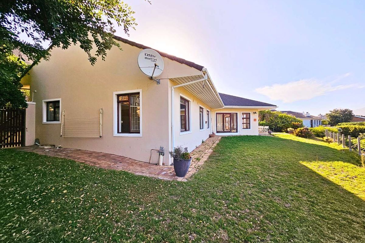 A view of the rear exterior of the house, featuring a paved walkway, lawn, and satellite dish mounted on the wall.