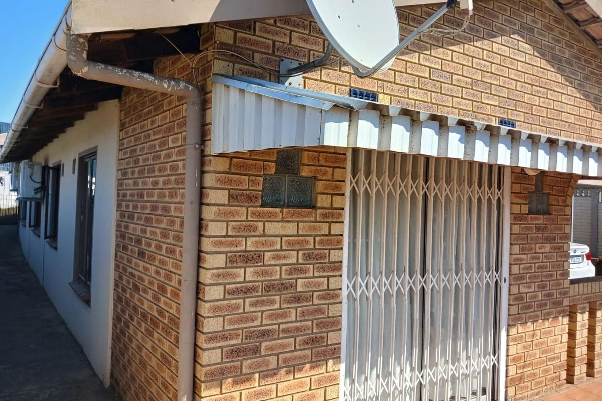Exterior view of the rear facade featuring face brick construction, a metal security gate, and a satellite dish installation.