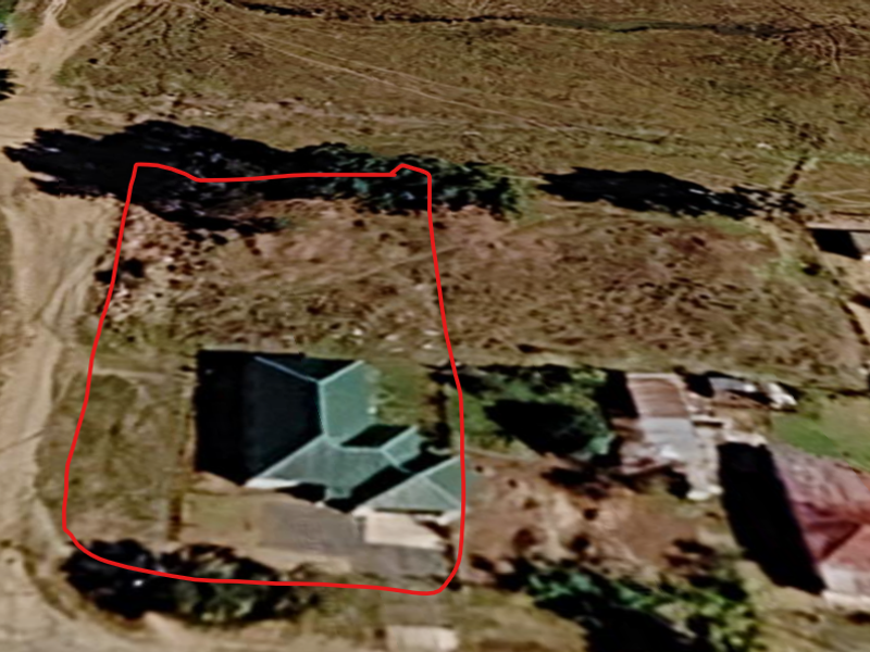 An aerial view of a residential property plot with an existing dwelling, showing the site boundaries and surrounding neighborhood context.