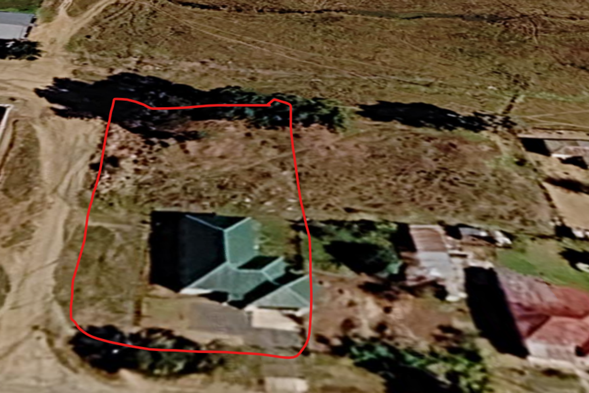 An aerial view of a residential property plot with an existing dwelling, showing the site boundaries and surrounding neighborhood context.