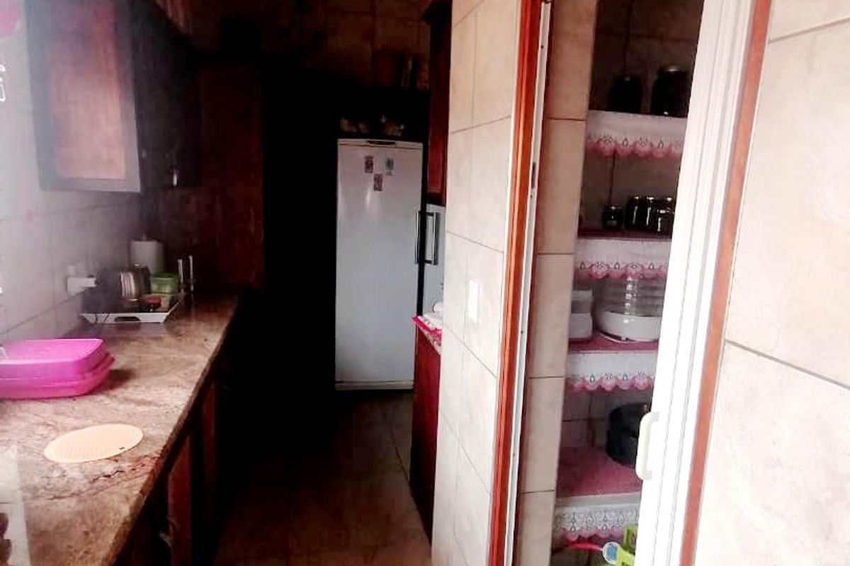 A functional kitchen area featuring granite countertops and a dedicated scullery or pantry space with built-in shelving.