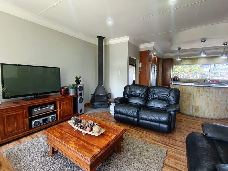 Open-plan living area featuring a freestanding fireplace, laminate flooring, and a stone-clad breakfast bar connecting to the kitchen space.