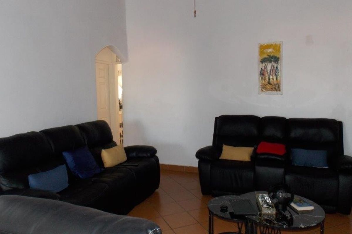A living room featuring tiled flooring and an arched doorway leading to an adjacent space.