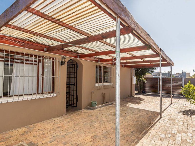 A covered outdoor patio area featuring a timber pergola with corrugated roofing and brick paving, providing a functional space for outdoor living.
