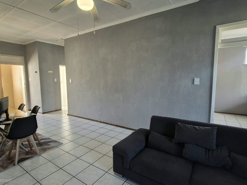 Open-plan living and dining area featuring tiled flooring, a ceiling fan, and neutral textured walls, providing a functional layout for daily living.