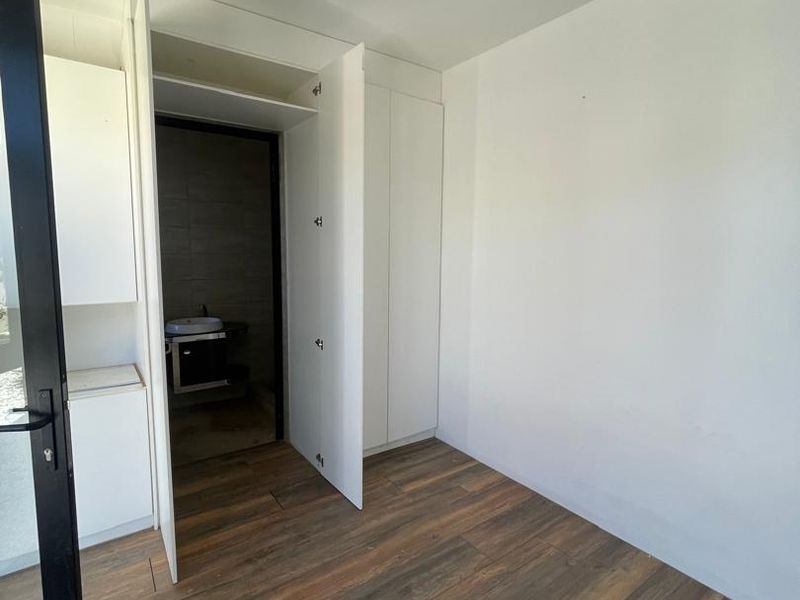An empty bedroom featuring laminate flooring, built-in wardrobe storage, and direct access to an en-suite bathroom.