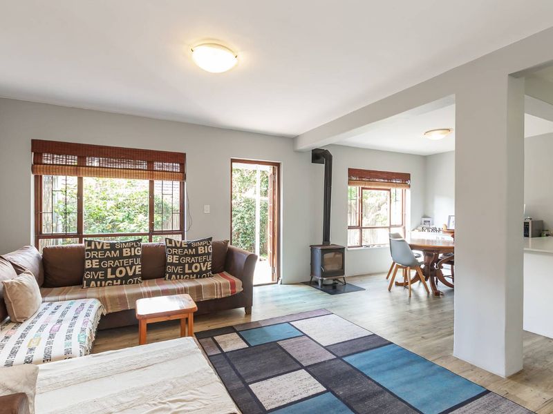 Open plan living and dining area featuring laminate flooring, a freestanding fireplace, and a functional kitchen with a breakfast island.