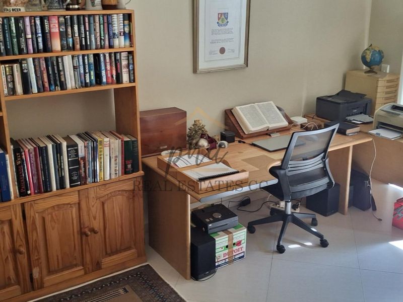 A functional home office space featuring tiled flooring and a sliding glass door providing natural light and access to the exterior.