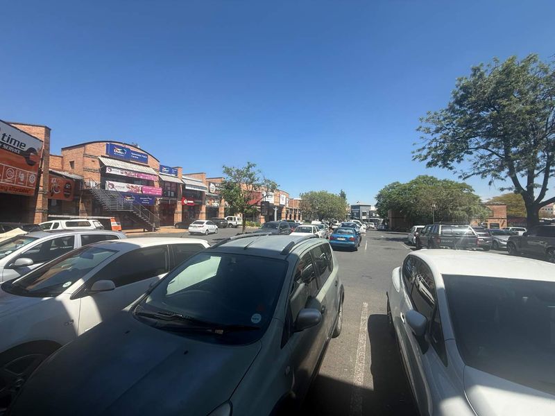 Exterior view of a commercial retail center featuring brick facades, external staircases, and a paved parking lot for customers.