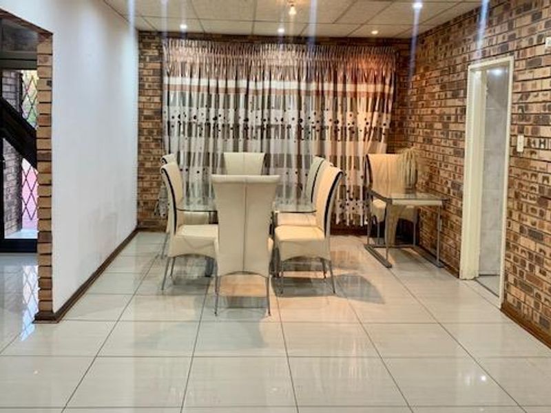 Dining area featuring exposed brick walls, polished tiled flooring, and recessed ceiling lighting, providing a rustic yet functional space for meals.