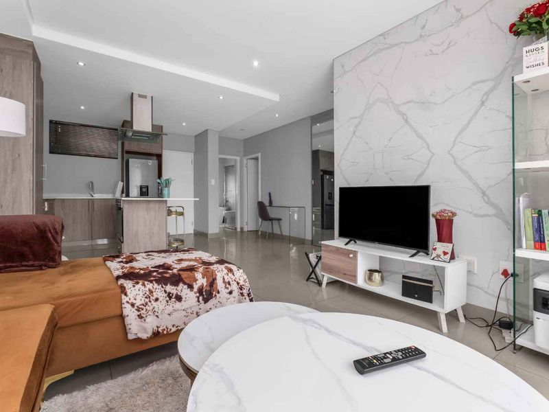 Modern open-plan living area featuring a marble-look feature wall, sleek kitchen cabinetry, and tiled flooring throughout.