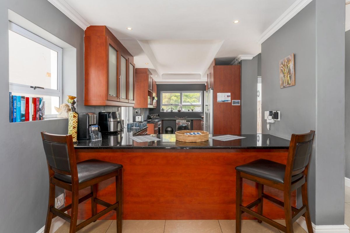 A functional kitchen featuring dark granite countertops, warm wood cabinetry, and a breakfast bar island, providing a practical space for cooking and casual dining.