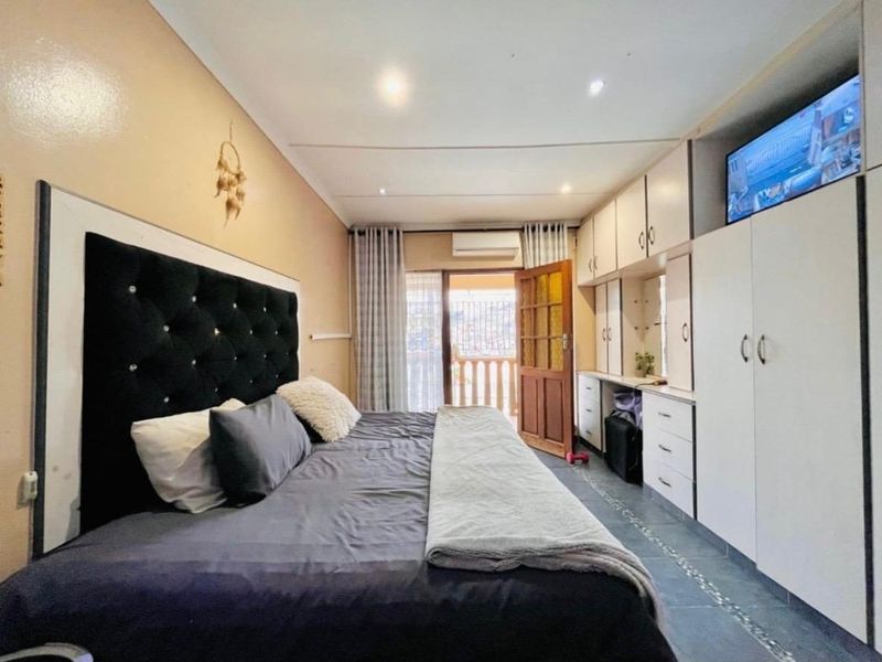 A bedroom featuring built-in cabinetry, tiled flooring, recessed lighting, and direct access to an outdoor balcony area.