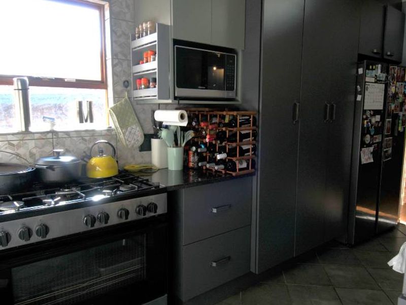 A functional kitchen featuring modern grey cabinetry, a gas stove with oven, tiled flooring, and a tiled backsplash.