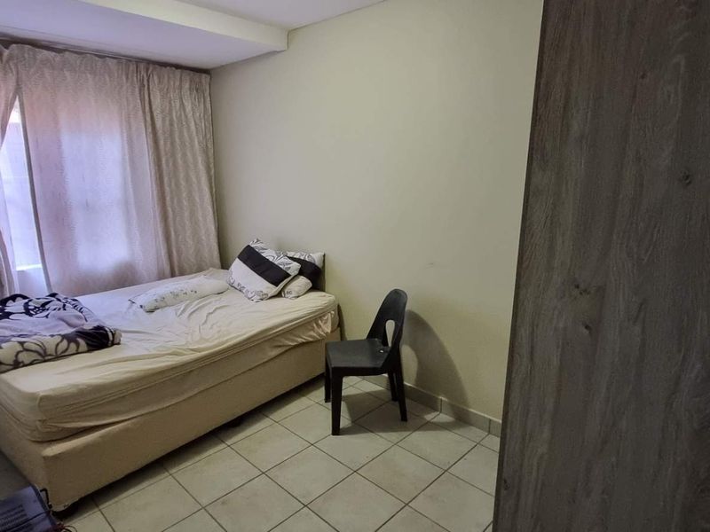 A functional bedroom featuring tiled flooring and a built-in cupboard, offering a simple and practical living space.