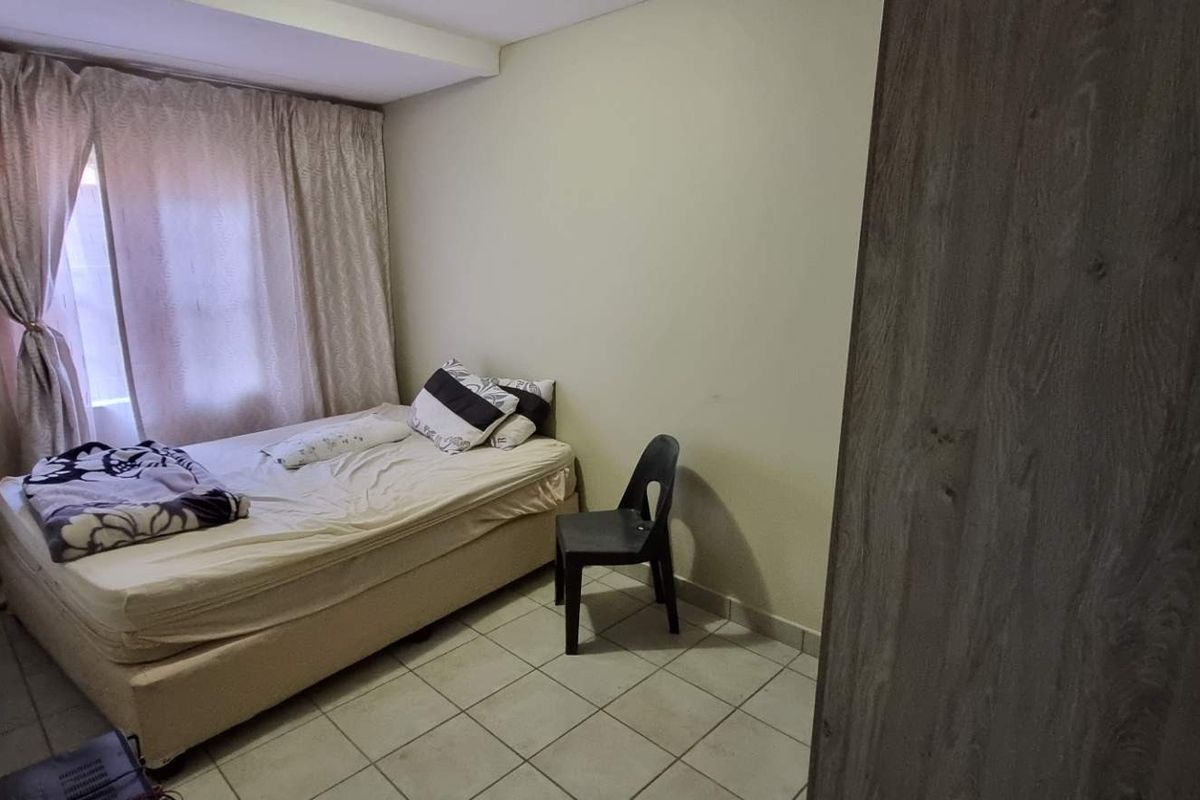 A functional bedroom featuring tiled flooring and a built-in cupboard, offering a simple and practical living space.
