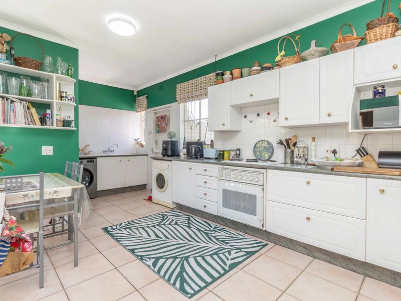 A functional kitchen featuring white cabinetry, tiled flooring, a built-in oven, and a tiled backsplash, offering a practical layout for daily meal preparation.