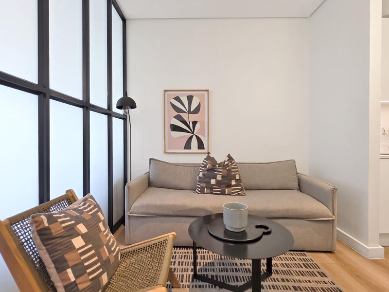 A modern living area featuring light timber flooring and a stylish black metal-framed glass partition, creating a bright and contemporary atmosphere.