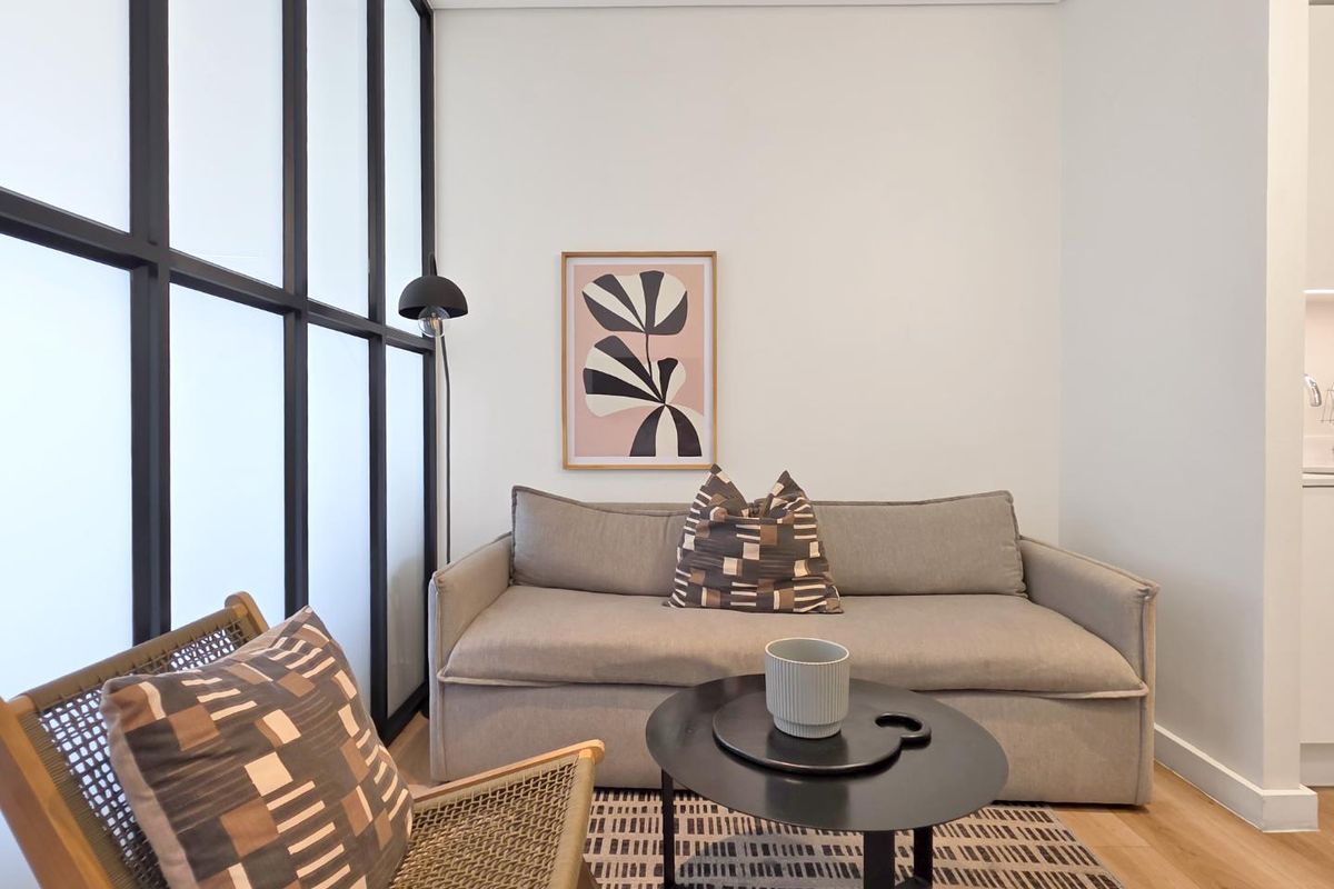 A modern living area featuring light timber flooring and a stylish black metal-framed glass partition, creating a bright and contemporary atmosphere.