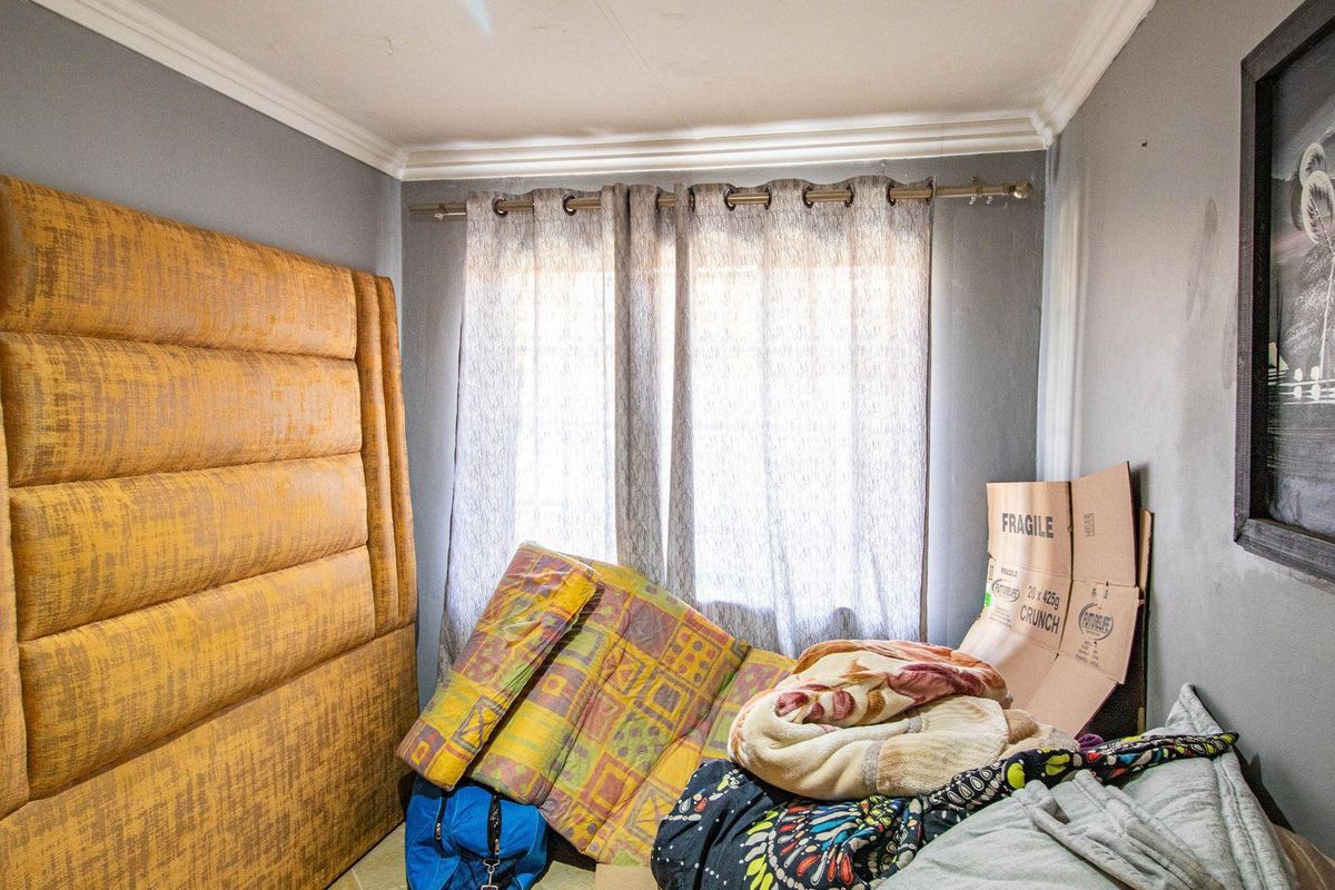 A compact bedroom featuring grey walls, crown molding, and a large built-in upholstered headboard panel.
