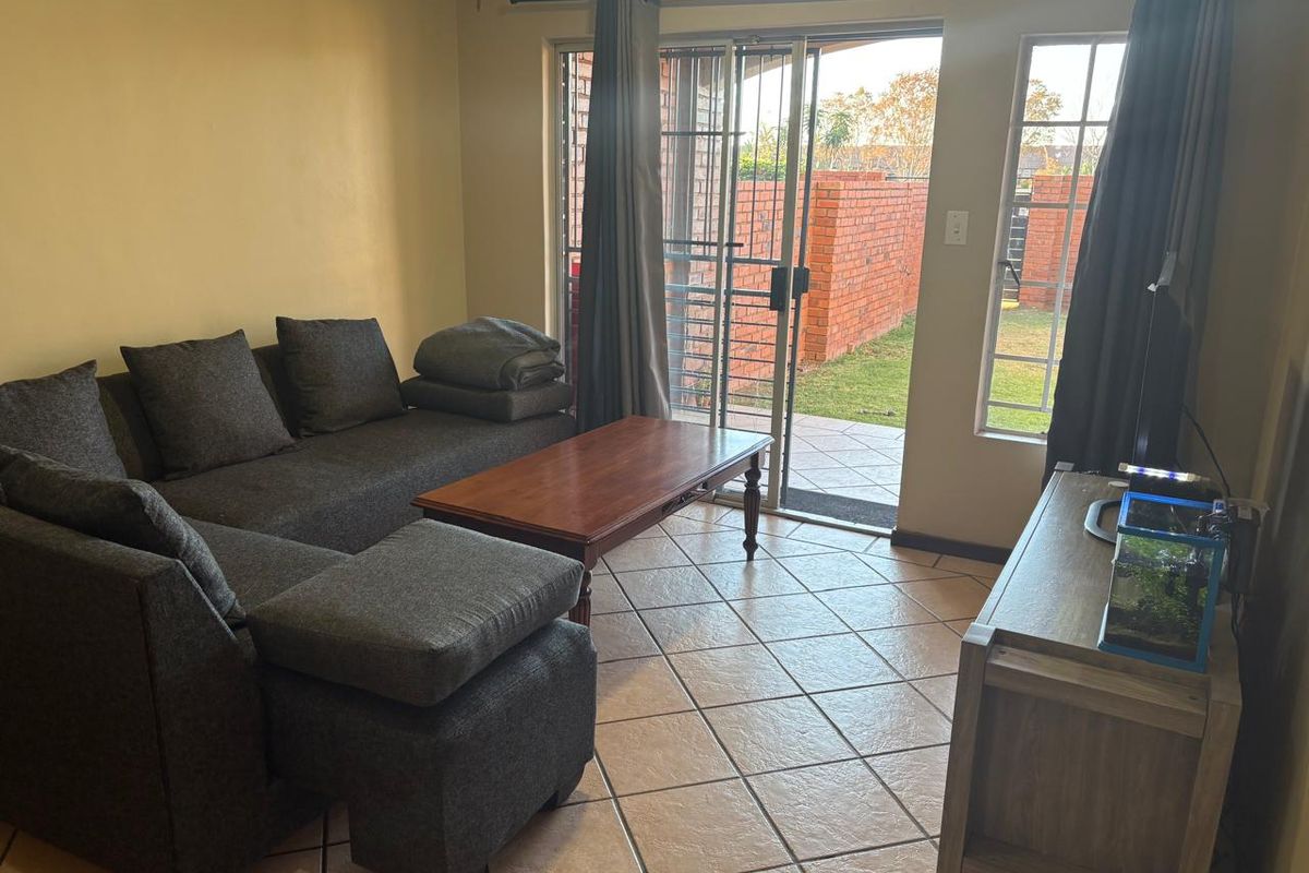A living room featuring ceramic floor tiles and a sliding glass door providing direct access to an outdoor patio area.