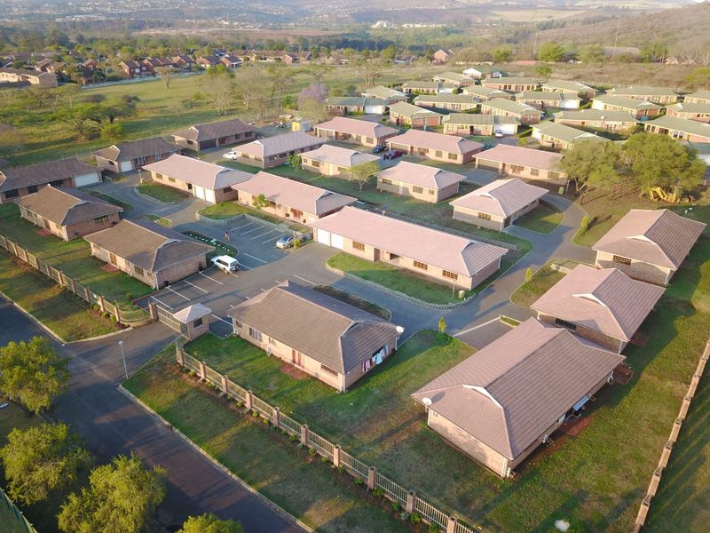 Aerial view of a residential townhouse complex featuring multiple units with tiled roofs, paved driveways, and secure perimeter fencing.