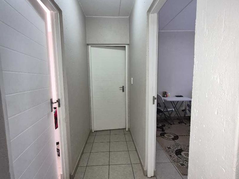 A functional hallway featuring tiled flooring and access to multiple rooms, illuminated by a central ceiling light fixture.