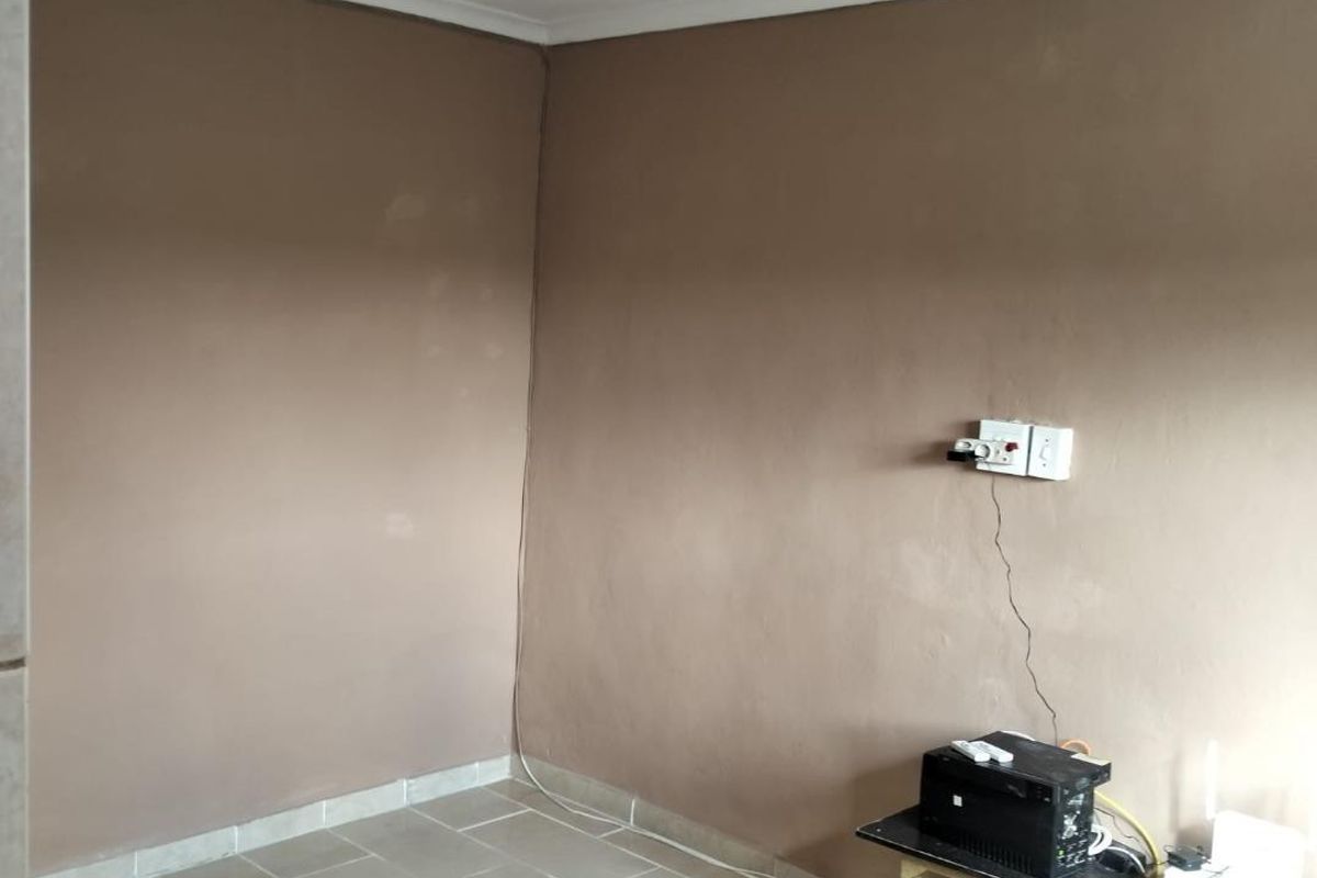 An empty living area featuring neutral tiled flooring and plain painted walls, providing a blank canvas for interior design and furnishing.