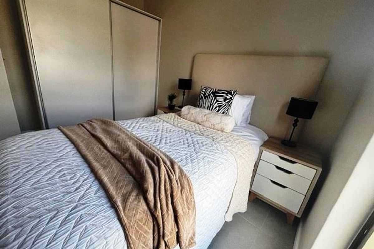 A well-maintained bedroom featuring built-in sliding door cupboards and neutral wall finishes, providing a clean and functional living space.