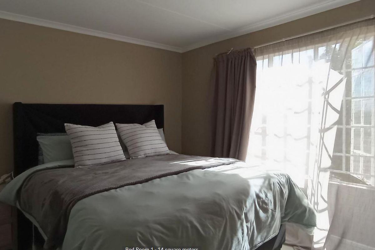 A bedroom featuring neutral wall tones, crown molding, and a large window allowing natural light, providing a comfortable and functional living space.