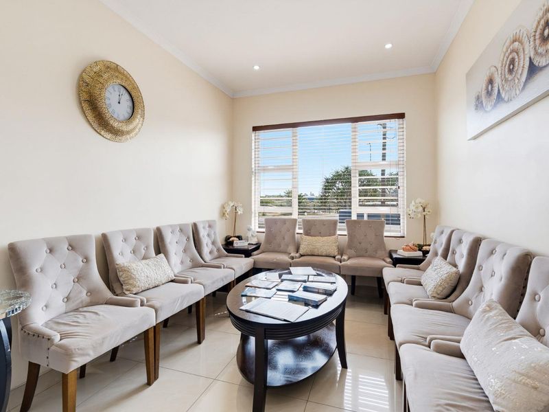 A well-maintained office waiting area featuring tiled flooring, recessed downlighting, and large windows with venetian blinds.