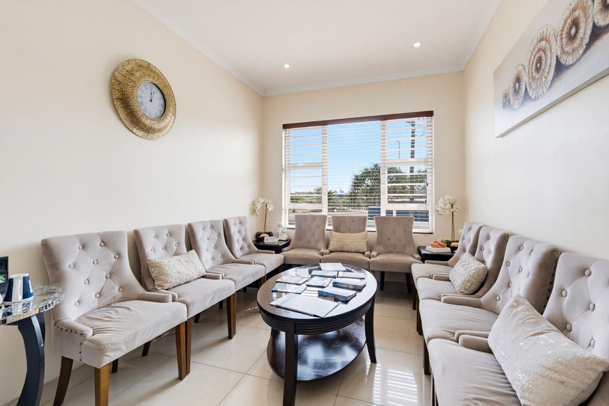A well-maintained office waiting area featuring tiled flooring, recessed downlighting, and large windows with venetian blinds.