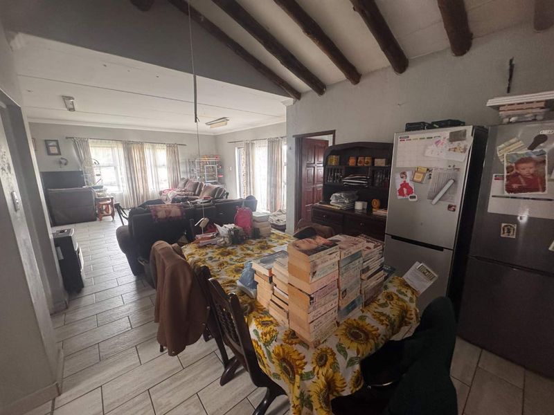 Open-plan living and dining area featuring exposed timber ceiling beams and tiled flooring, creating a spacious and functional layout for family living.