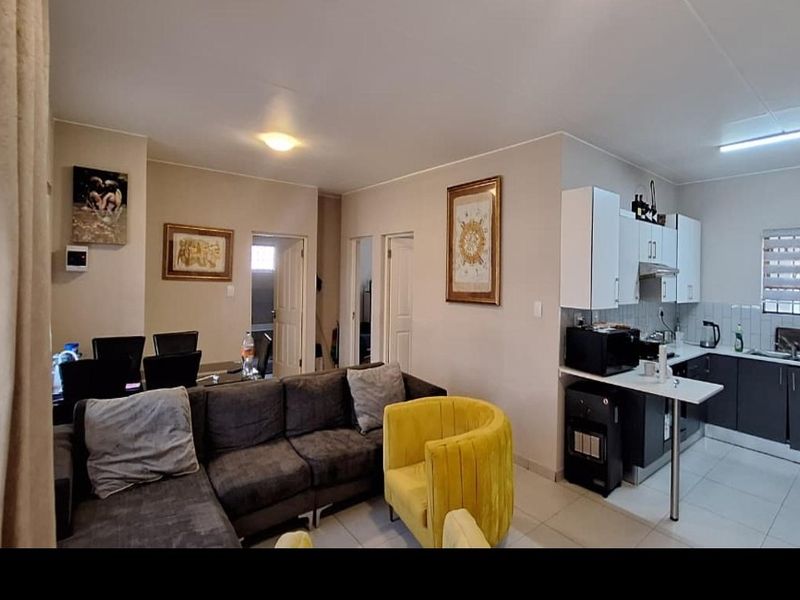 Open-plan living and kitchen area featuring tiled flooring, modern cabinetry, and a breakfast bar, creating a functional and connected living space.