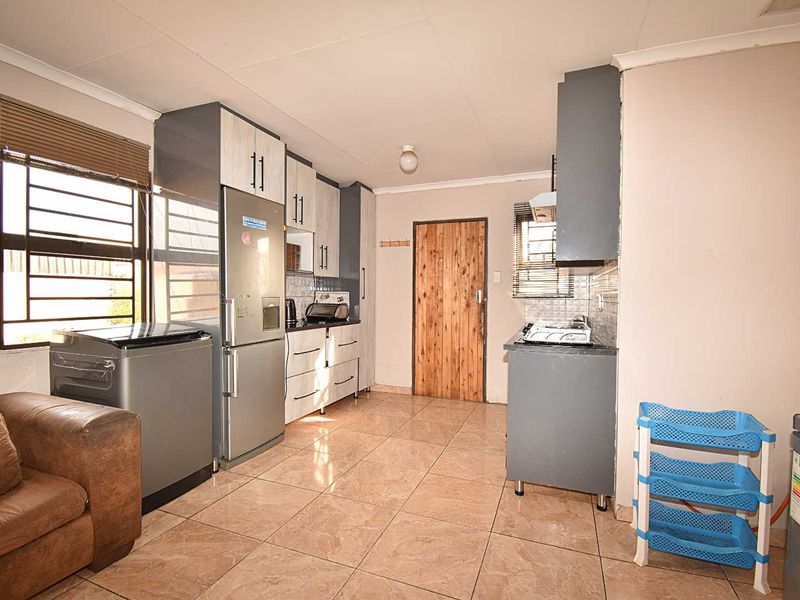 Functional kitchen featuring tiled flooring, built-in cabinetry, and a hob with extractor fan, offering a practical layout for daily meal preparation.
