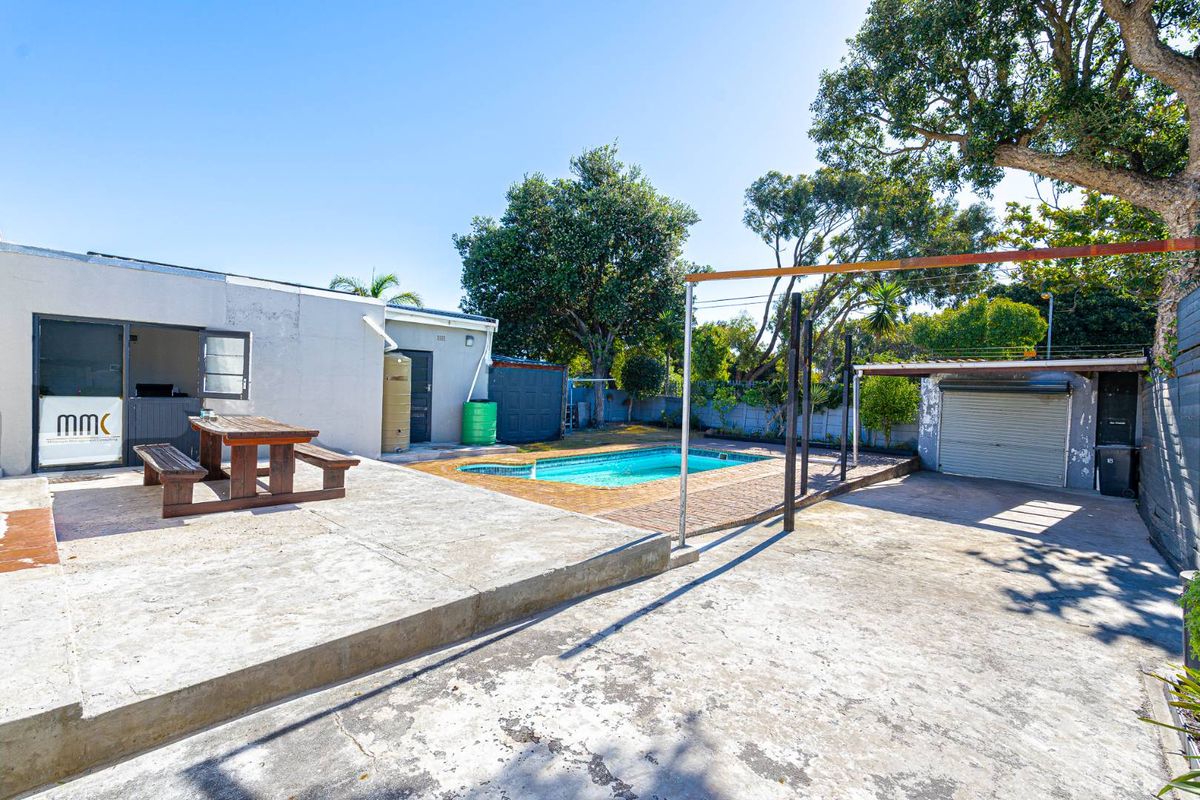 Rear outdoor area featuring a swimming pool, concrete patio space, and a detached garage structure.
