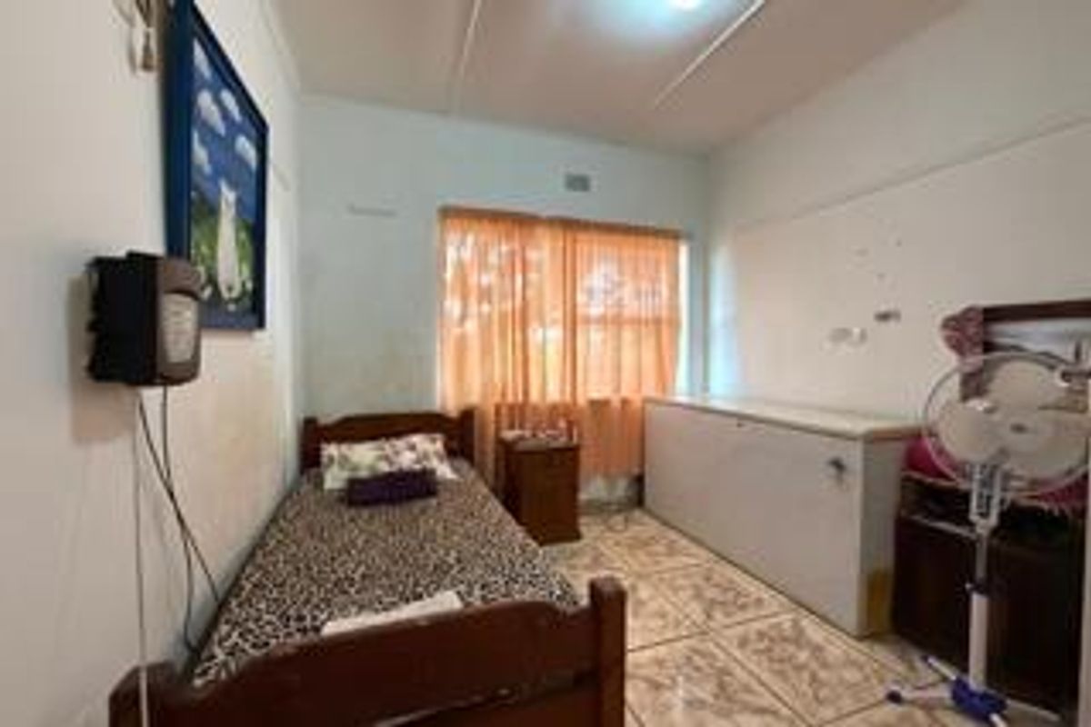 A compact bedroom featuring tiled flooring and a window with curtains, providing a functional space for rest.