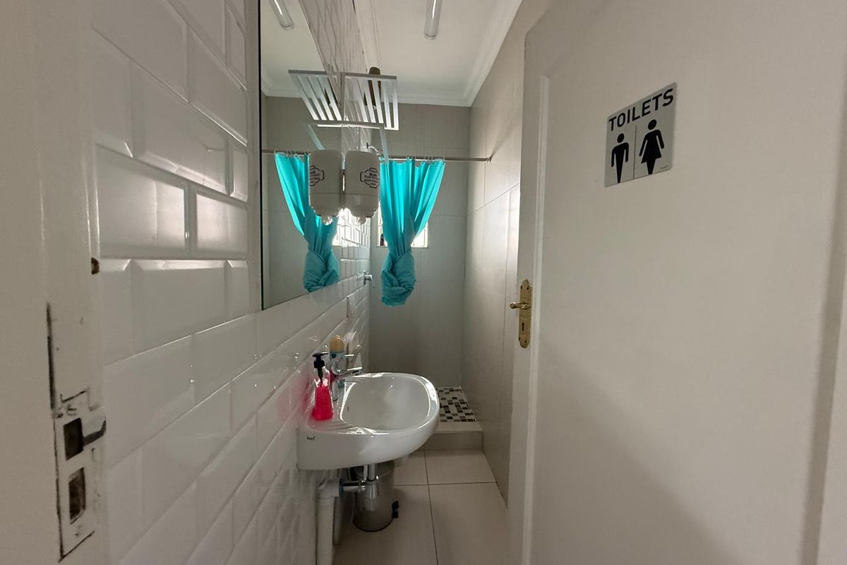 A functional restroom facility featuring white subway wall tiling, a wall-mounted basin, and a dedicated toilet entrance.