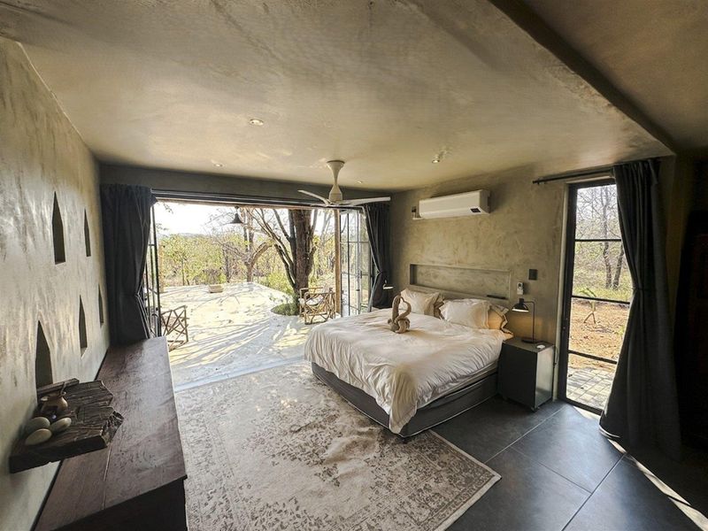 Spacious bedroom featuring polished concrete-style walls, tiled flooring, a ceiling fan, and large sliding doors opening to a private outdoor patio area.