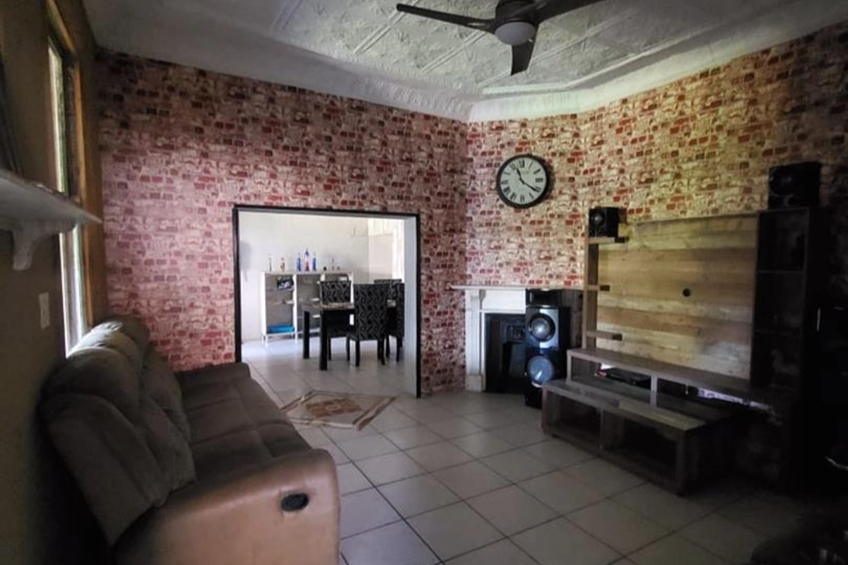 A living room featuring a decorative ceiling, tiled flooring, and a fireplace, with an open transition to the adjacent dining area.