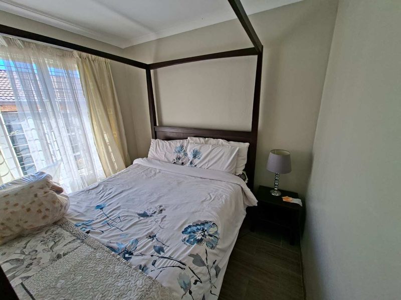 A bedroom featuring tiled flooring and coved ceiling details, providing a functional space with natural light from the window.