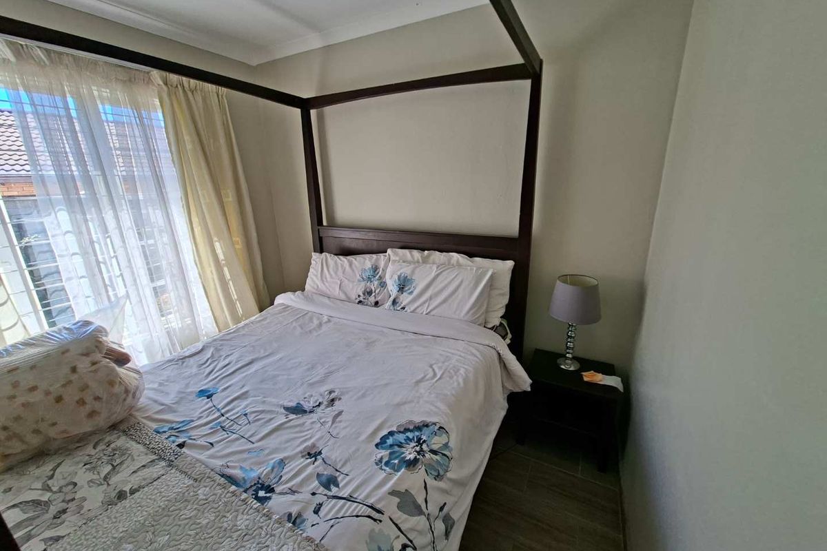 A bedroom featuring tiled flooring and coved ceiling details, providing a functional space with natural light from the window.