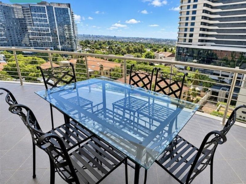 Spacious balcony featuring modern tiled flooring and a sleek stainless steel balustrade, offering expansive elevated views of the surrounding cityscape.